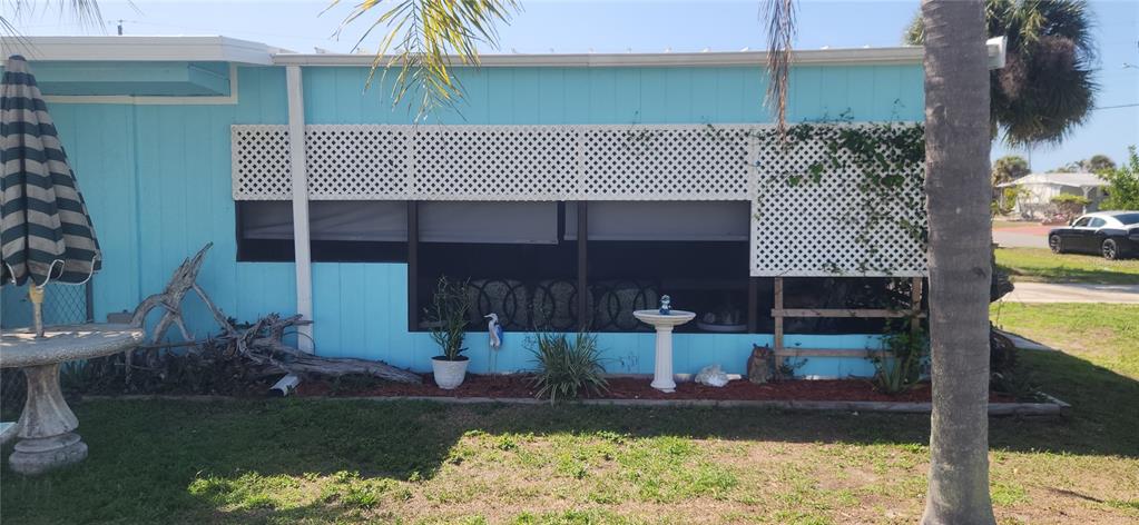 A light blue mobile home exterior features a screened-in porch with white lattice privacy panels — 324 CALLE LIANA, ENGLEWOOD, FL