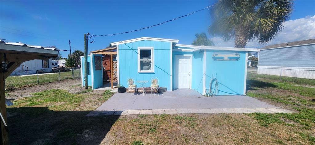 A light blue mobile home features a small concrete patio, a white door, and windows — 324 CALLE LIANA, ENGLEWOOD, FL