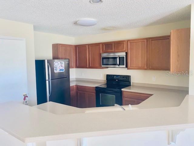 A kitchen features wood cabinets, stainless steel appliances, and a light-colored countertop — 1064 CHALCEDONY STREET, KISSIMMEE, FL