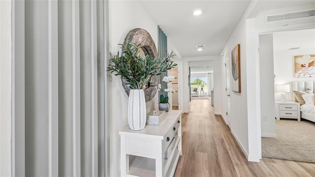 A white console table with a vase and mirror sits in a hallway with wood-look flooring — 6843 SW 42ND COURT ROAD, OCALA, FL