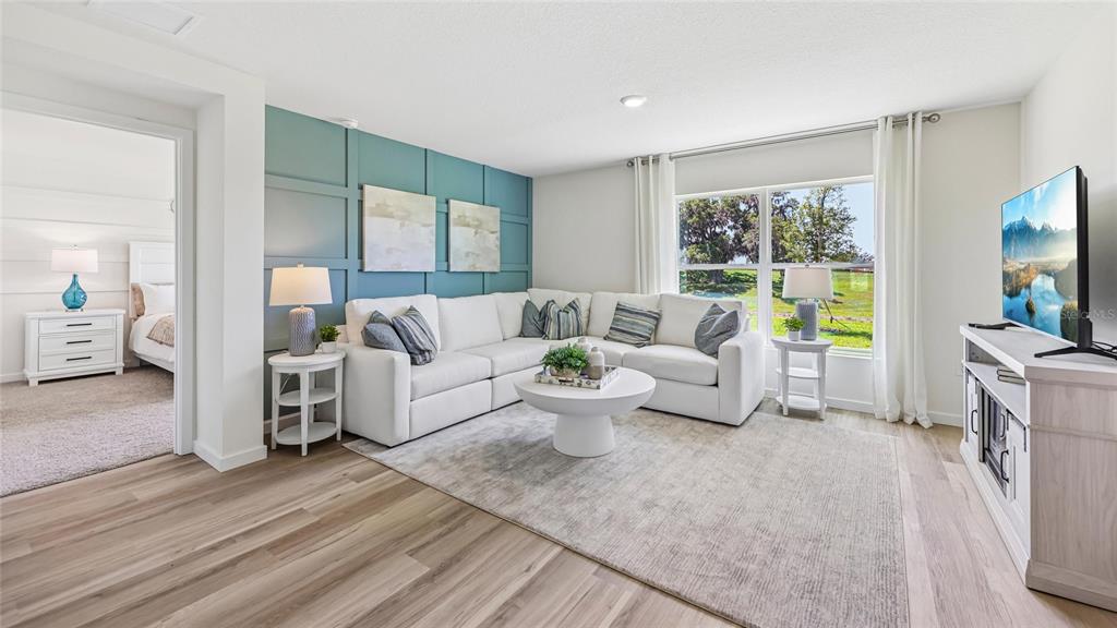 A living room features a white sectional sofa, blue paneled accent wall, and wood flooring — 6843 SW 42ND COURT ROAD, OCALA, FL