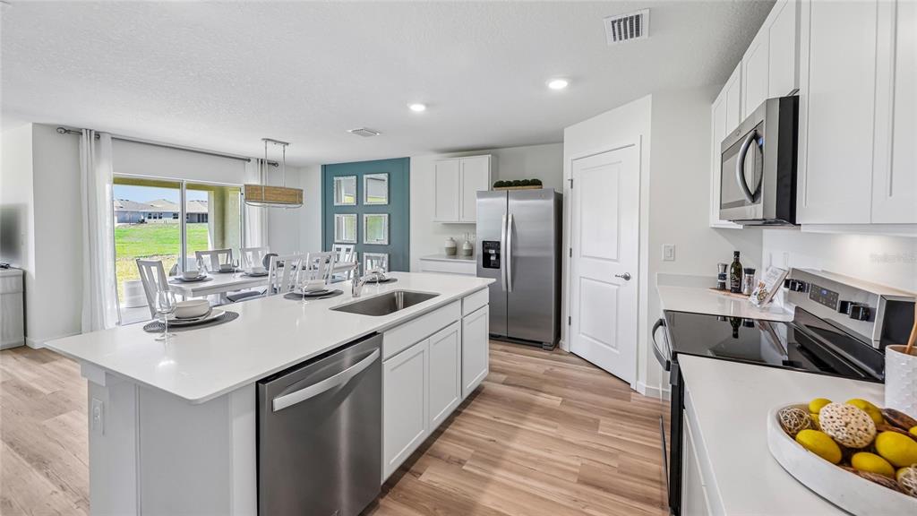 A modern kitchen features white cabinets, stainless steel appliances, and a large central island — 6843 SW 42ND COURT ROAD, OCALA, FL