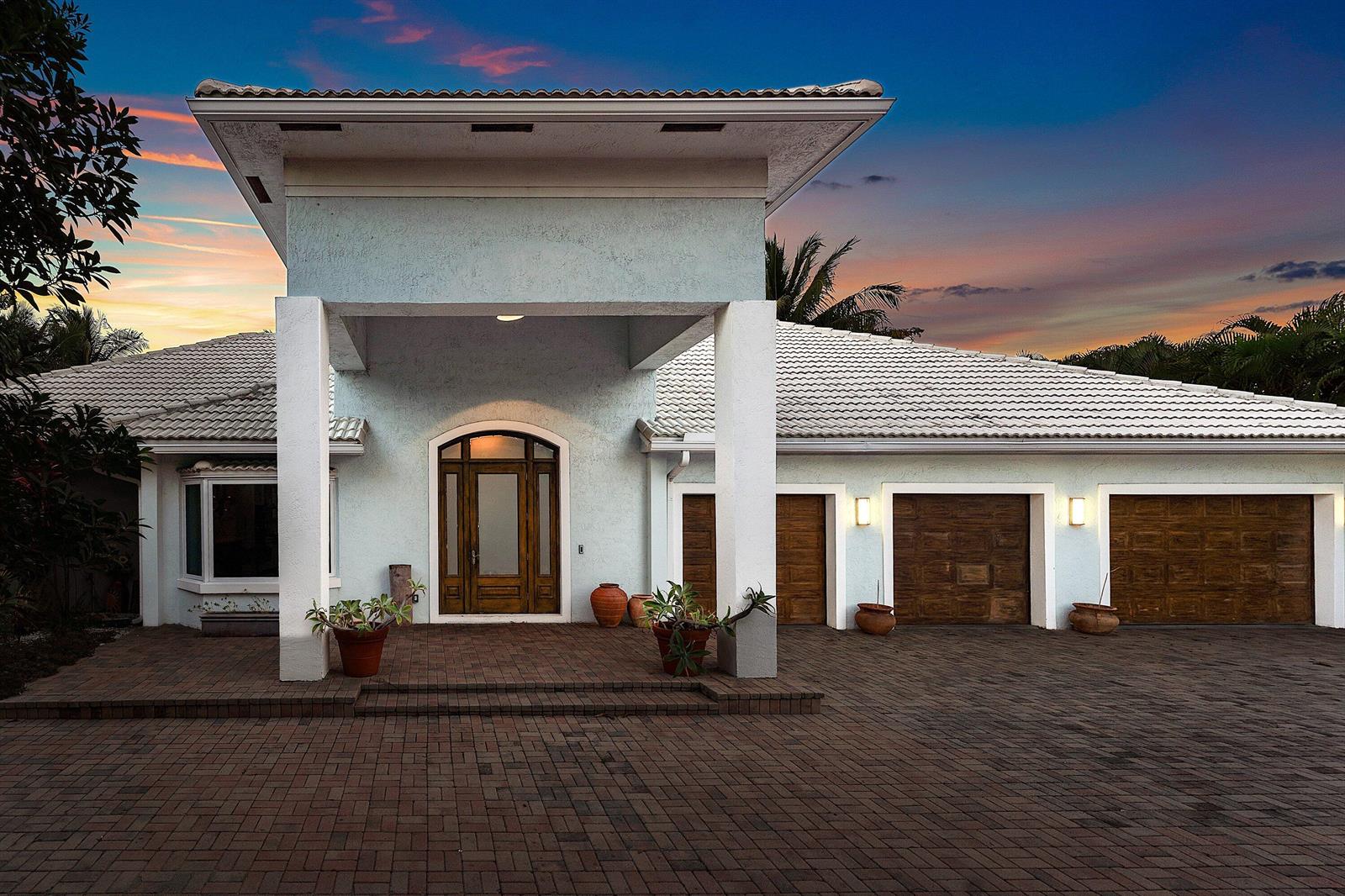 A light blue house with a covered entryway, arched front door, and three garage bays — 2311 NE 47th Street, Lighthouse Point FL 33064, LIGHTHOUSE POINT, FL