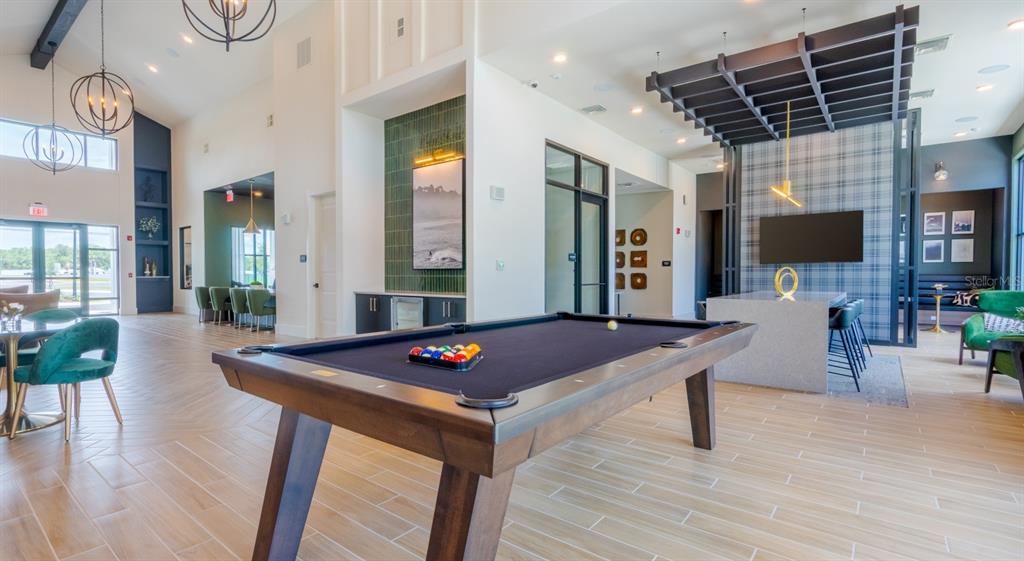A spacious clubhouse lounge features a pool table, modern lighting, and contemporary seating areas — 18772 GRAND LIVE OAK BOULEVARD UNIT A2.1, LAND O LAKES, FL