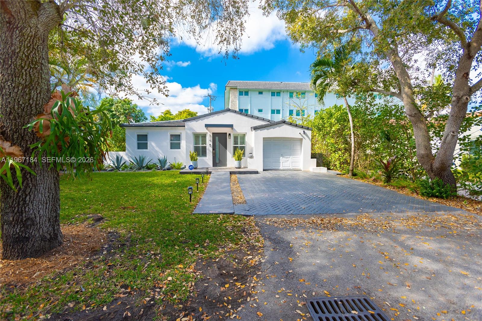 A white single-story house features a paved driveway, a one-car garage, and a front lawn — 814 Monterey St, Coral Gables FL 33134, CORAL GABLES, FL