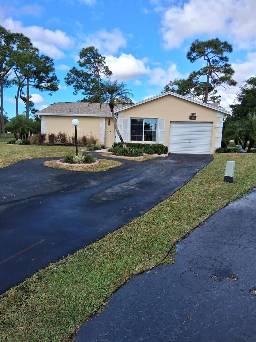 A single-story house with a beige exterior, a white garage door, and a paved driveway — 4703 Rainbow Drive, FL 33463, FL