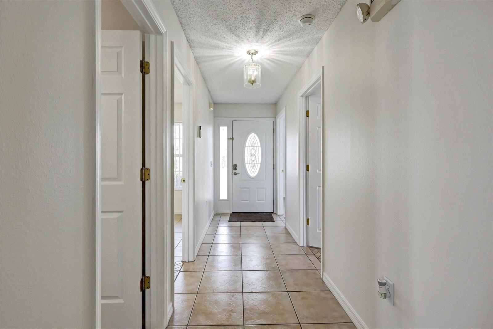 A tiled hallway leads to a white front door with a decorative glass insert — 1175 Jaybee Avenue, Davenport FL 33897, DAVENPORT, FL