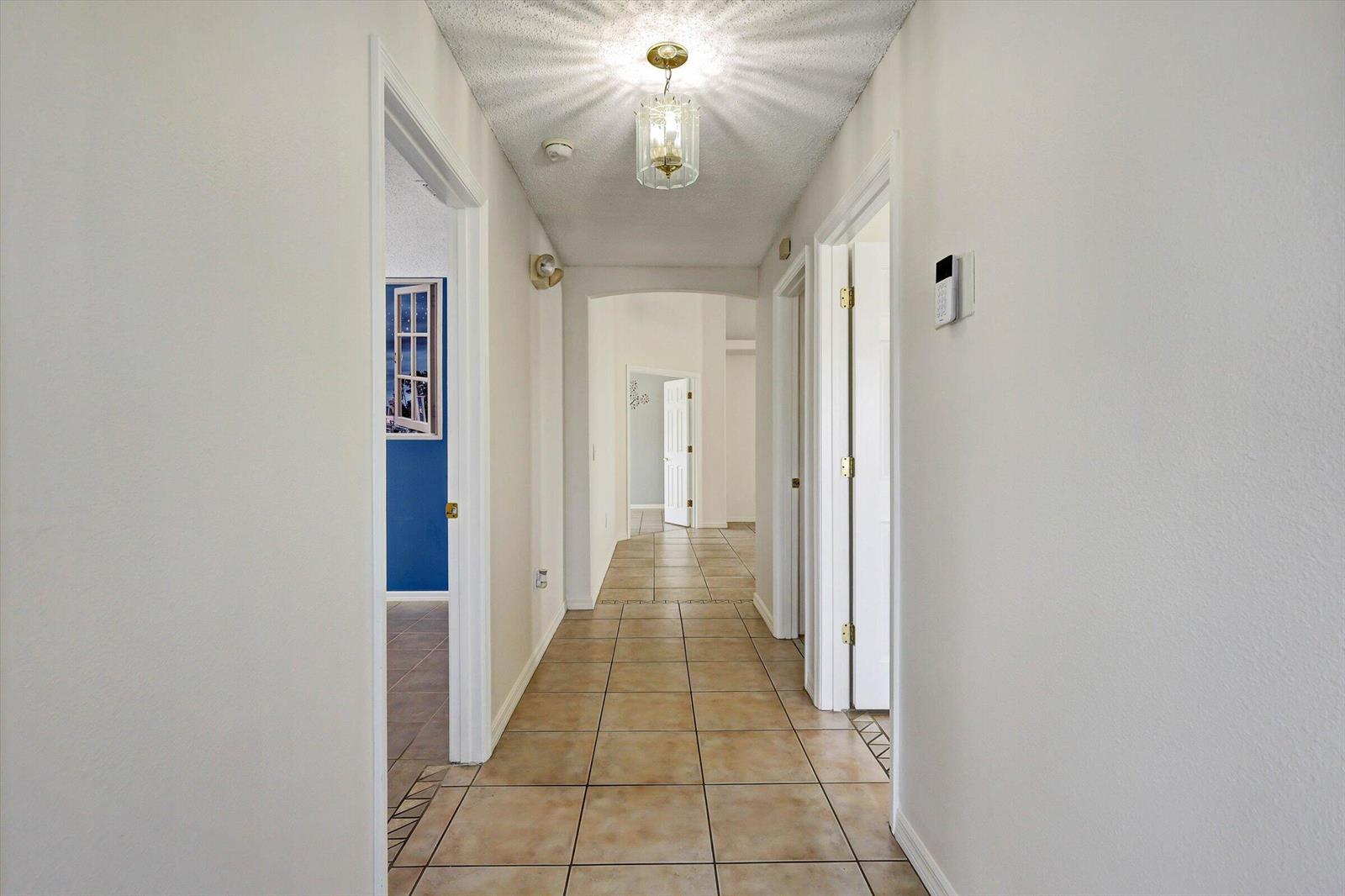 A hallway with tan tile flooring, white walls, and a central ceiling light fixture — 1175 Jaybee Avenue, Davenport FL 33897, DAVENPORT, FL