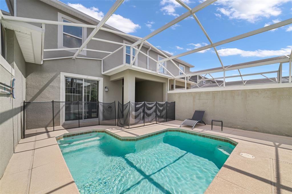 A backyard swimming pool with a safety fence is enclosed by a screened-in patio structure — 388 OCEAN COURSE AVENUE, DAVENPORT, FL