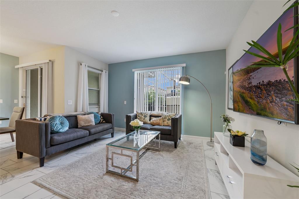 A living room features a grey sofa, a glass coffee table, and a wall-mounted television — 388 OCEAN COURSE AVENUE, DAVENPORT, FL