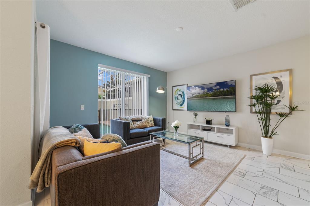 A living room features a blue accent wall, tile flooring, a television, and two sofas — 388 OCEAN COURSE AVENUE, DAVENPORT, FL