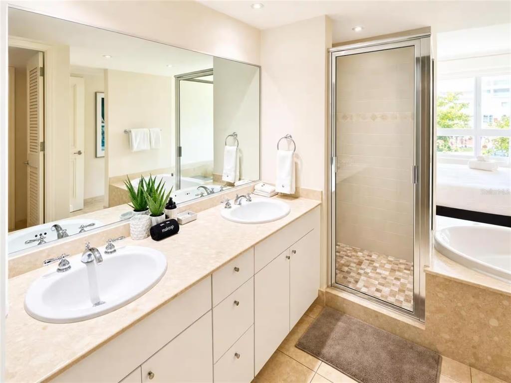 A bathroom features a double vanity with white cabinets, a glass shower, and a soaking tub — 100 OCEAN DRIVE UNIT 131, HUMACAO, PR