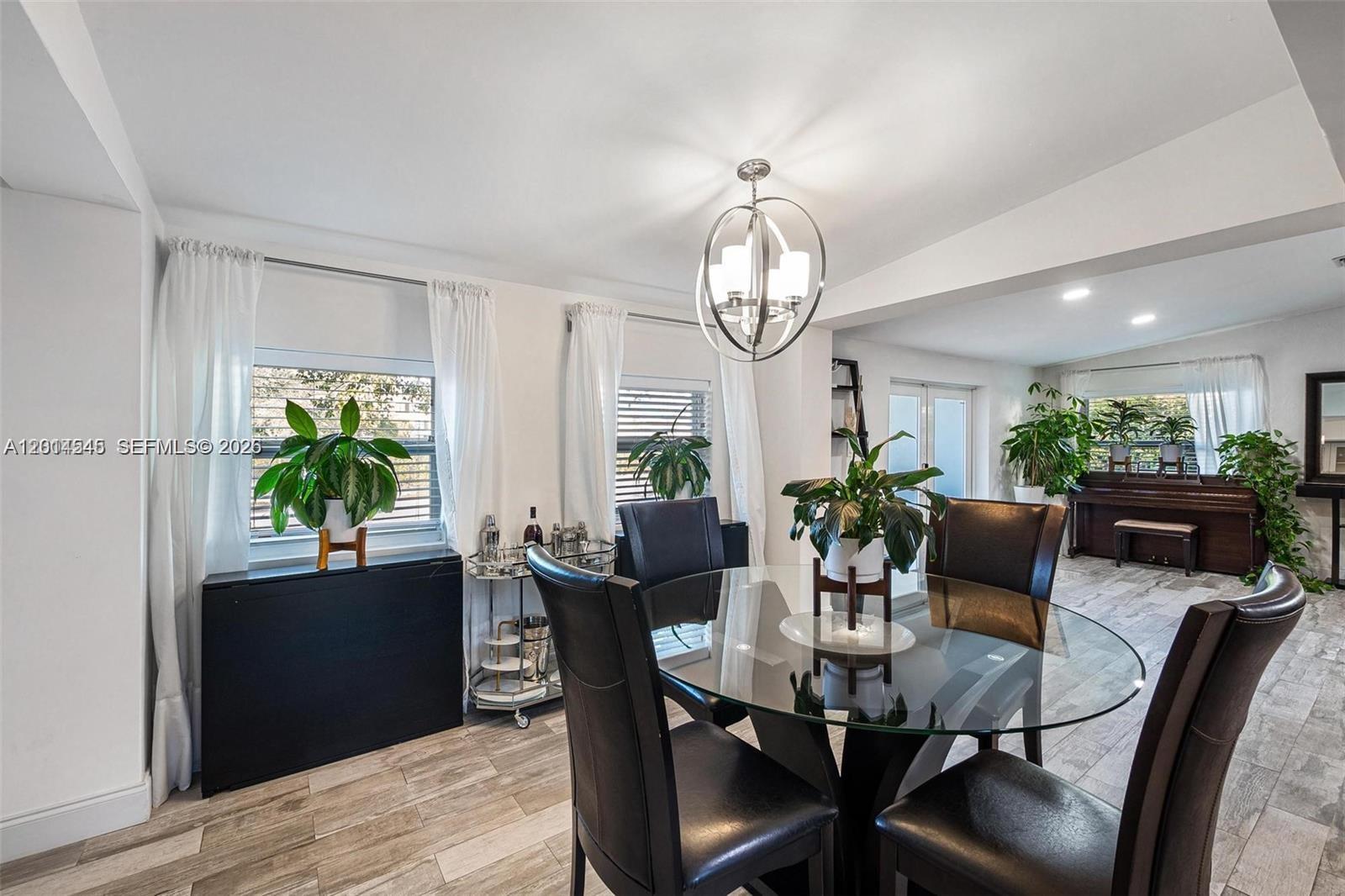 A dining area features a glass-topped table, dark chairs, and a modern chandelier — 1946 SW 20th St # 1946, Miami FL 33145, MIAMI, FL