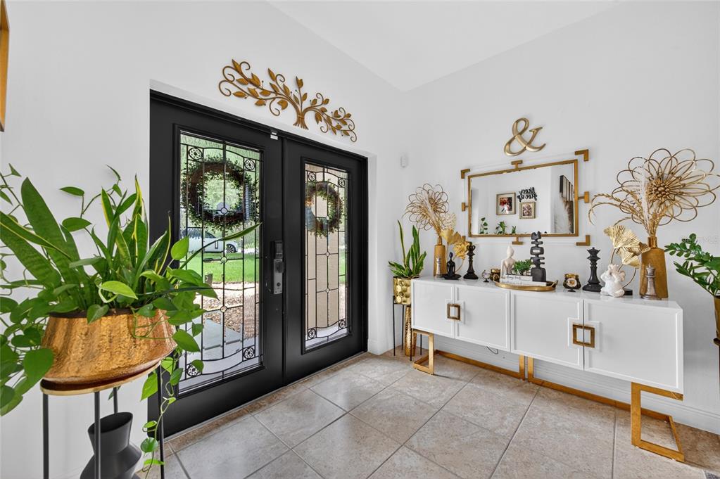 A bright entryway features a black double door, tiled flooring, and a white console table — 1801 WATERSIDE OAKS DRIVE, ORANGE CITY, FL