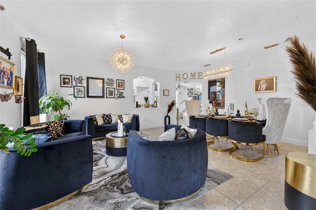 A living and dining room area features navy blue velvet furniture and gold-accented light fixtures — 1801 WATERSIDE OAKS DRIVE, ORANGE CITY, FL