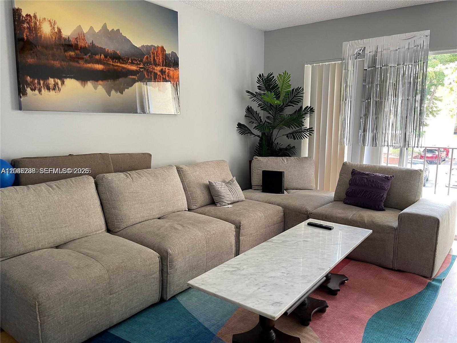 A living room features a modular beige sofa, a marble coffee table, and a colorful rug — 12035 NE 2nd Ave # A209, North Miami FL 33161, NORTH MIAMI, FL