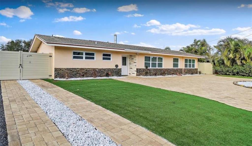 A single-story house with a stone facade, a paved driveway, and a green lawn — 245 78 TH AVENUE N, ST PETERSBURG, FL
