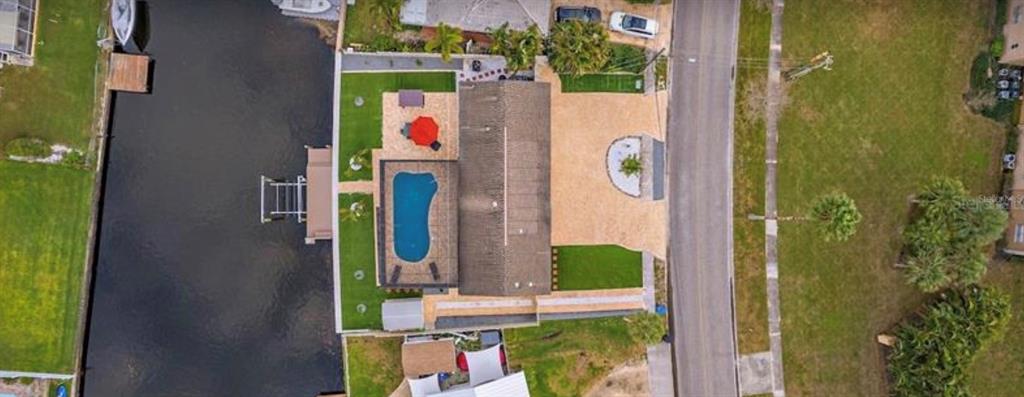 An aerial view shows a house with a swimming pool, patio, and dock along a canal — 245 78 TH AVENUE N, ST PETERSBURG, FL