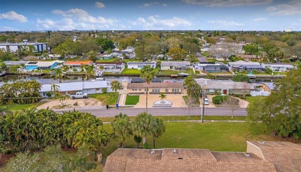 An aerial view shows a residential street with houses, a canal, and palm trees — 245 78 TH AVENUE N, ST PETERSBURG, FL