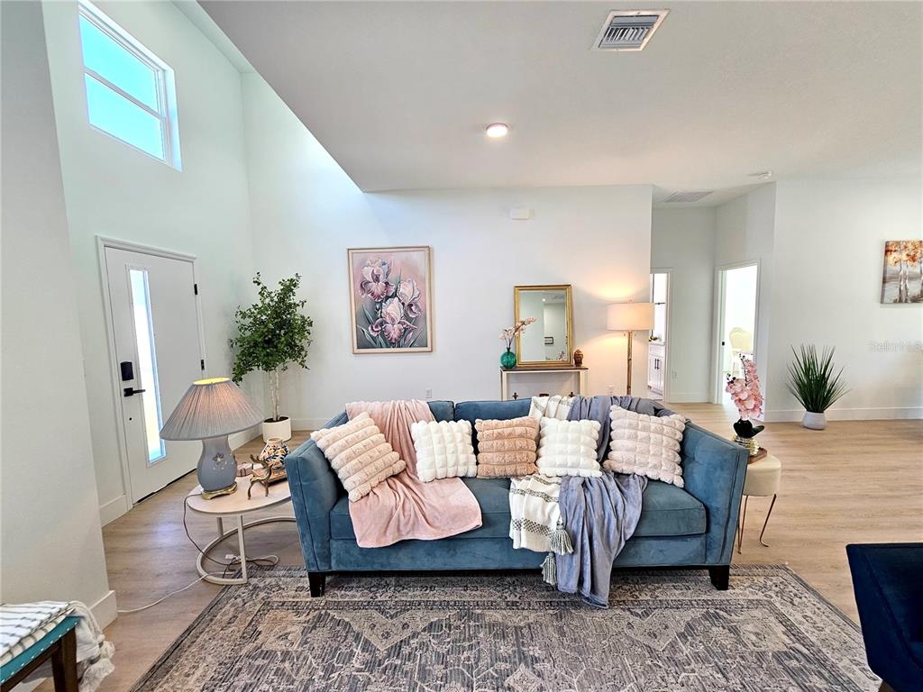 A blue sofa sits on a patterned rug in a living room with high ceilings — 2523 SW 153RD PLACE ROAD, OCALA, FL