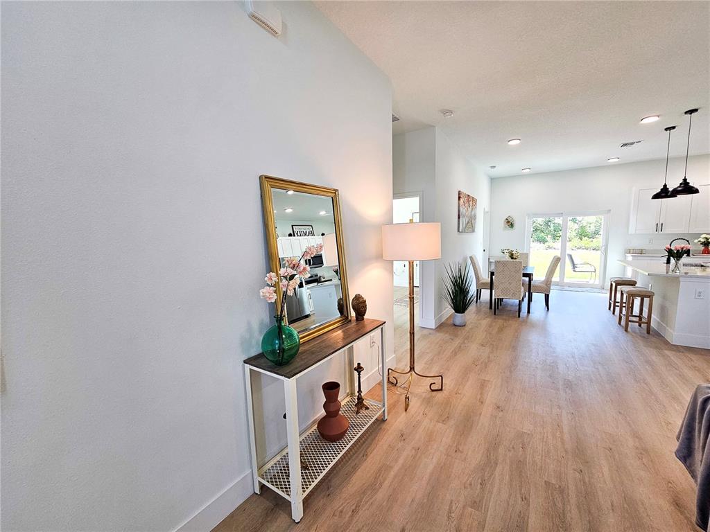 An entryway console table with a mirror leads into an open-concept kitchen and dining area — 2523 SW 153RD PLACE ROAD, OCALA, FL