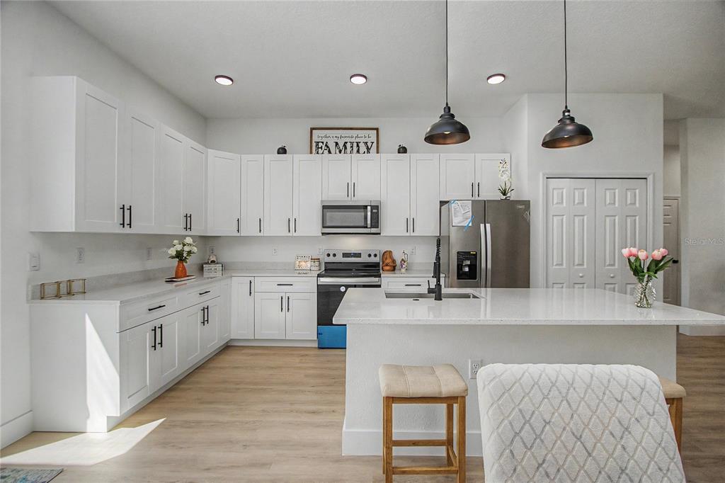 A bright kitchen features white shaker cabinets, stainless steel appliances, and a central island — 2523 SW 153RD PLACE ROAD, OCALA, FL