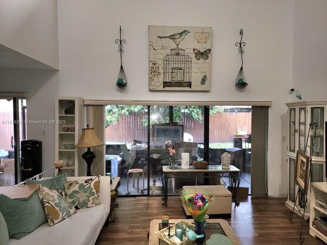 A living room features a high ceiling, a large bird-themed wall art, and sliding glass doors — 11060 SW 143rd Pl, Miami FL 33186, MIAMI, FL