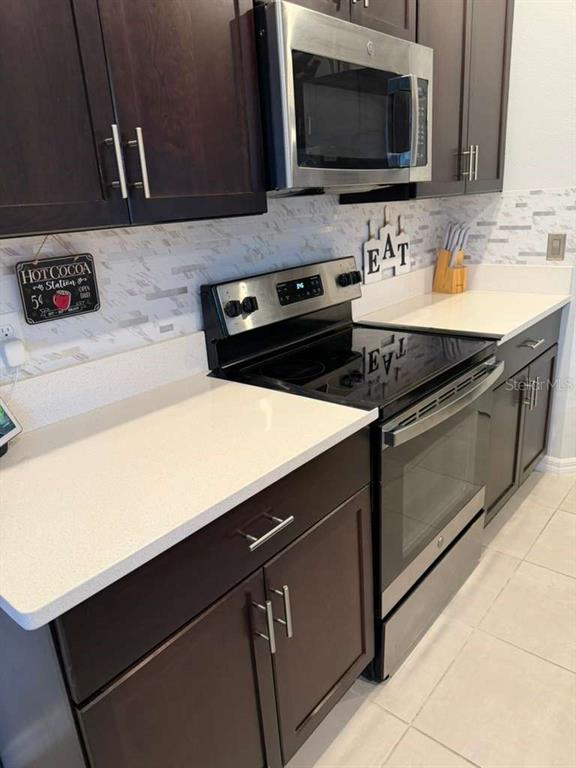 A kitchen features dark wood cabinets, stainless steel appliances, and white quartz countertops — 3589 ANIBAL STREET, KISSIMMEE, FL