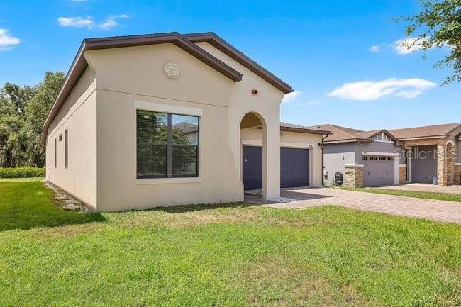 A single-story house with a tan stucco exterior and a dark-colored garage — 9248 CHANDLER DRIVE, GROVELAND, FL