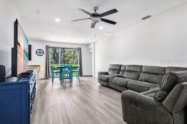 A living room features a gray sectional sofa, a television on a blue console, and dining area — 9248 CHANDLER DRIVE, GROVELAND, FL