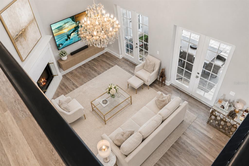 A bright living room features a fireplace, a large chandelier, and glass doors to a patio — 10370 TROUT ROAD, ORLANDO, FL