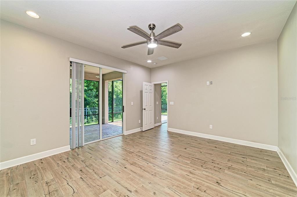 An empty room with wood-look tile flooring, a ceiling fan, and sliding glass doors — 12821 BALSAM TERRACE, BRADENTON, FL