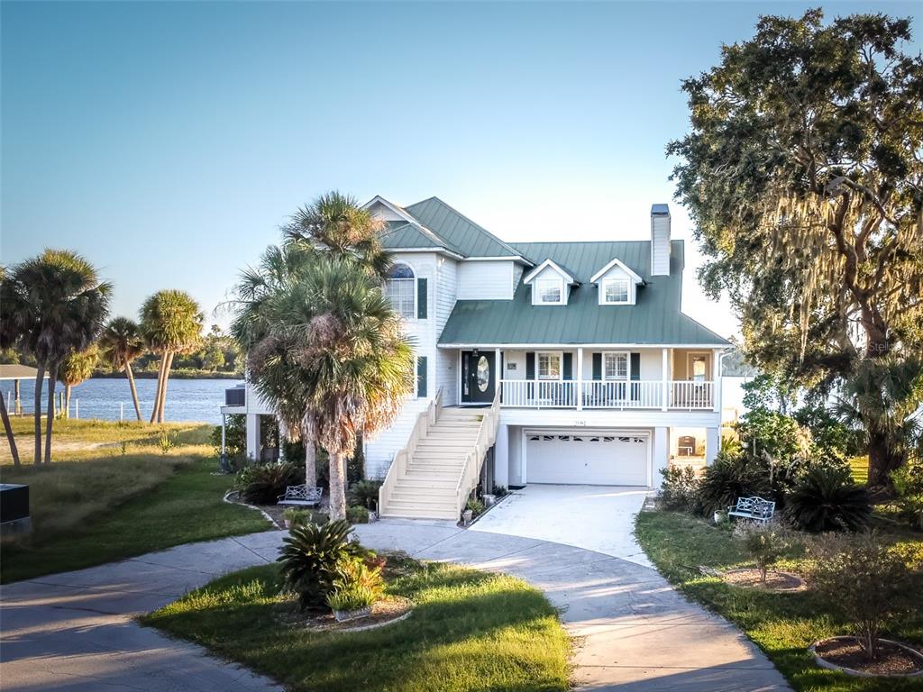 A two-story white house with a green metal roof sits near a body of water — 2130 NW 14TH STREET, CRYSTAL RIVER, FL