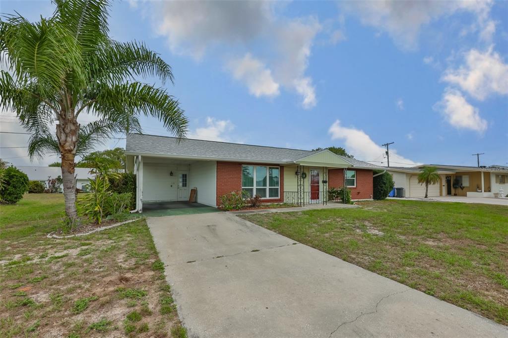 A single-story house with a brick facade, a carport, and a palm tree in the yard — 1216 VALLEY FORGE BOULEVARD, SUN CITY CENTER, FL