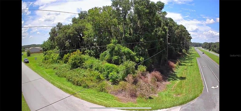 An aerial view shows a two-lane road winding through a rural landscape with green fields — Corner SE 142ND PLACE & S US HWY-301, SUMMERFIELD, FL
