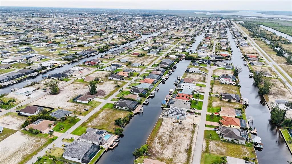 An aerial view shows residential houses along canals in a suburban neighborhood — 718 NW 38TH PLACE, CAPE CORAL, FL
