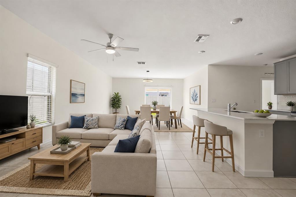 An open-concept living room and kitchen area with light tile flooring and neutral furniture — 1721 WHITE WATER COURT, DAVENPORT, FL
