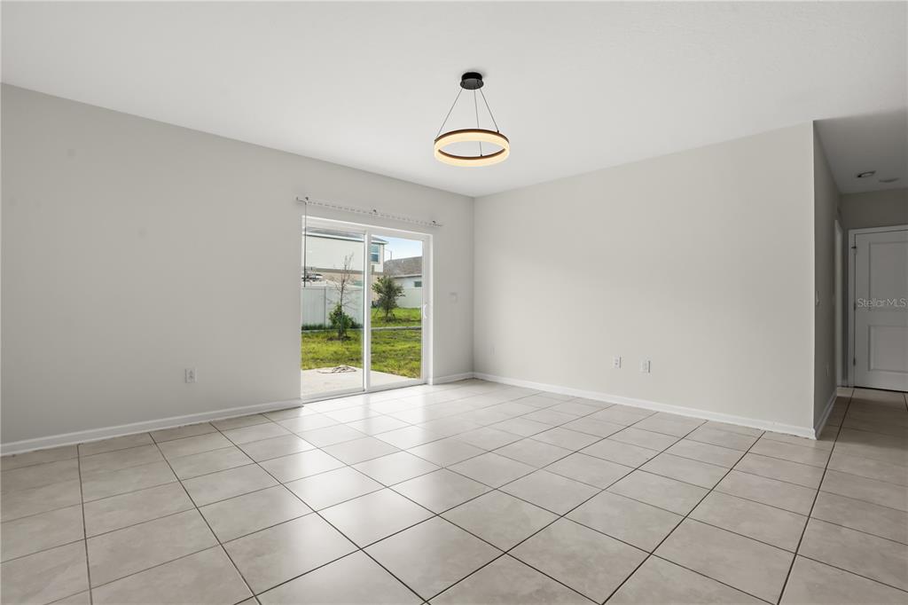An empty room features light-colored tile flooring, white walls, and a modern circular pendant light — 1721 WHITE WATER COURT, DAVENPORT, FL