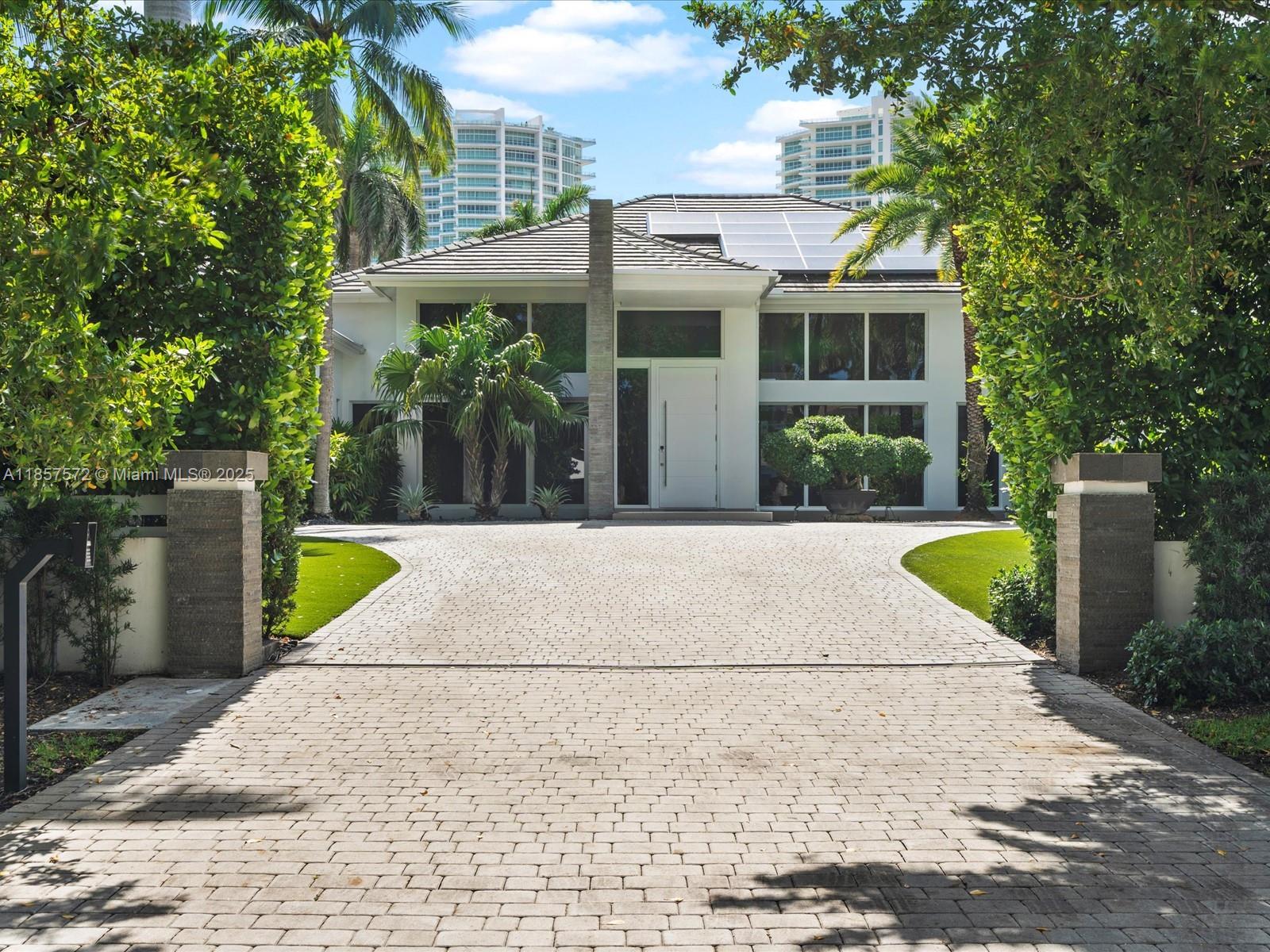 A paved driveway leads to the front entrance of a modern house with solar panels — 224 S ISLAND, Golden Beach FL 33160, GOLDEN BEACH, FL