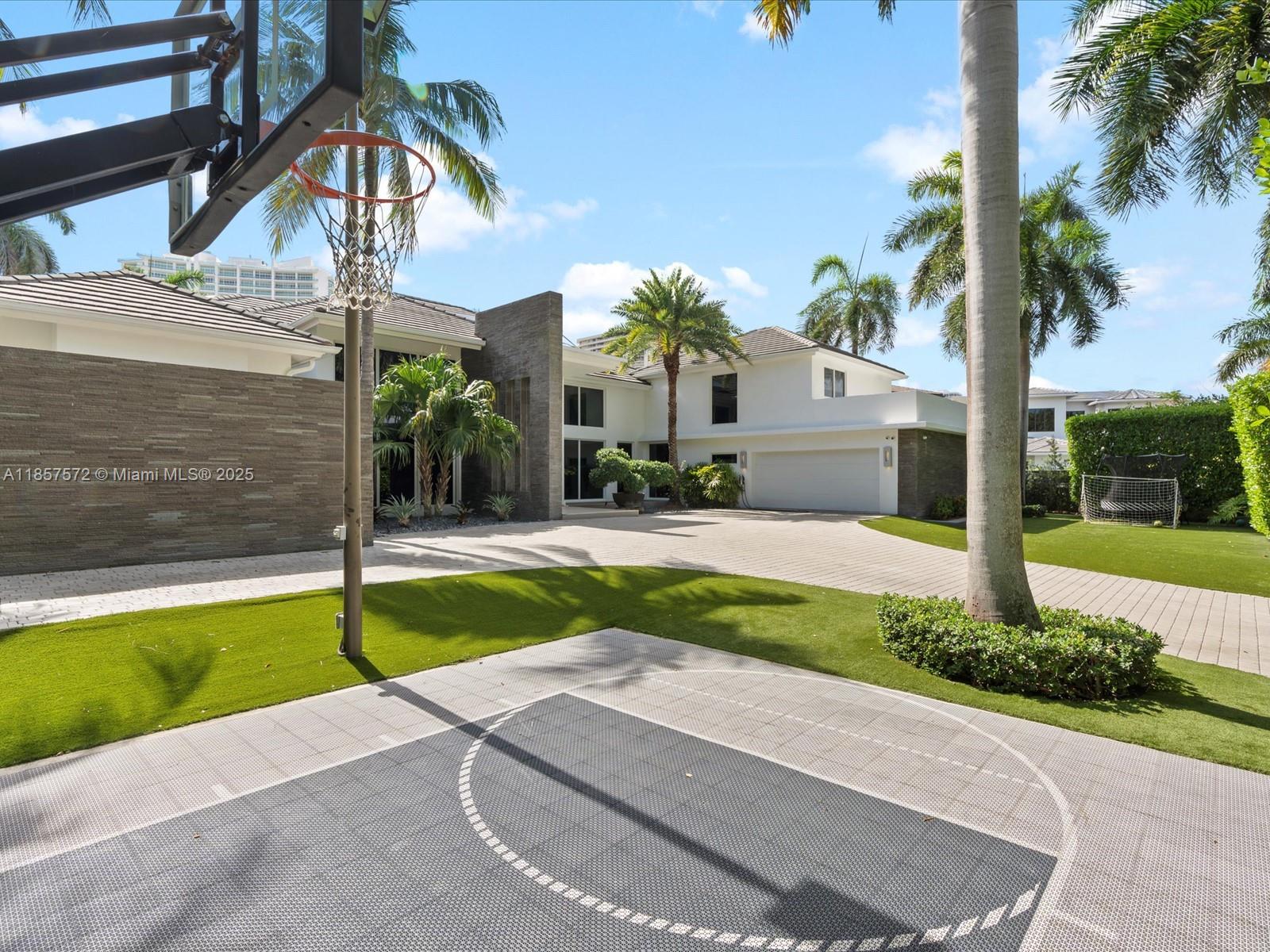 A modern house exterior features a basketball court, a paved driveway, and several palm trees — 224 S ISLAND, Golden Beach FL 33160, GOLDEN BEACH, FL