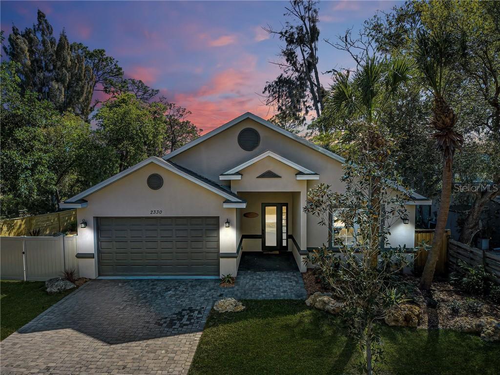 A single-story house with a paved driveway, garage, and front entrance under a sunset sky — 2330 BRADFORD STREET, SARASOTA, FL
