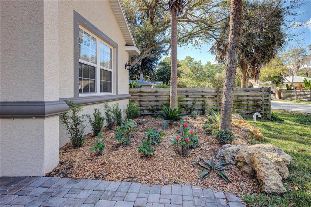 A side view of a house exterior featuring a landscaped garden bed with wood mulch — 2330 BRADFORD STREET, SARASOTA, FL
