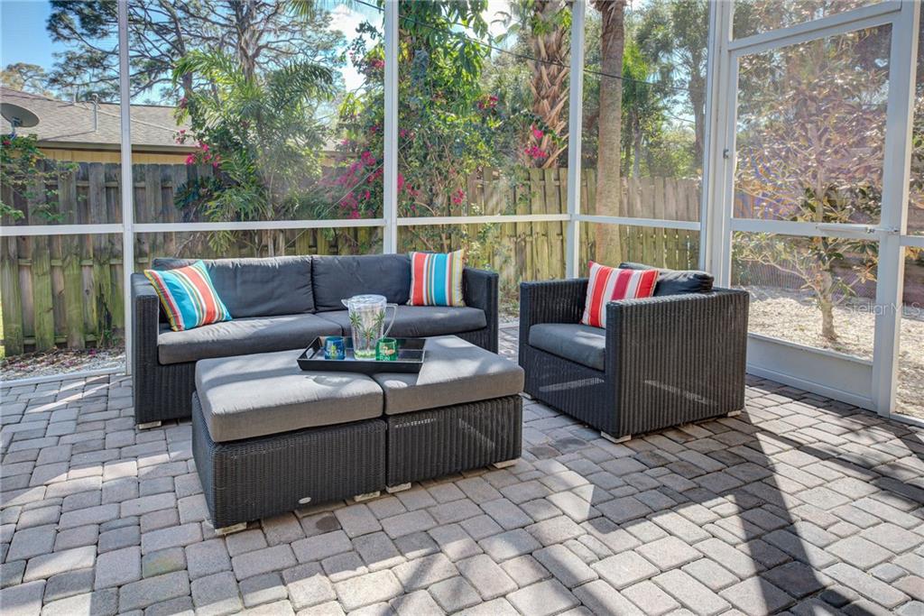 A screened-in patio features dark wicker furniture with gray cushions on a paved floor — 2330 BRADFORD STREET, SARASOTA, FL