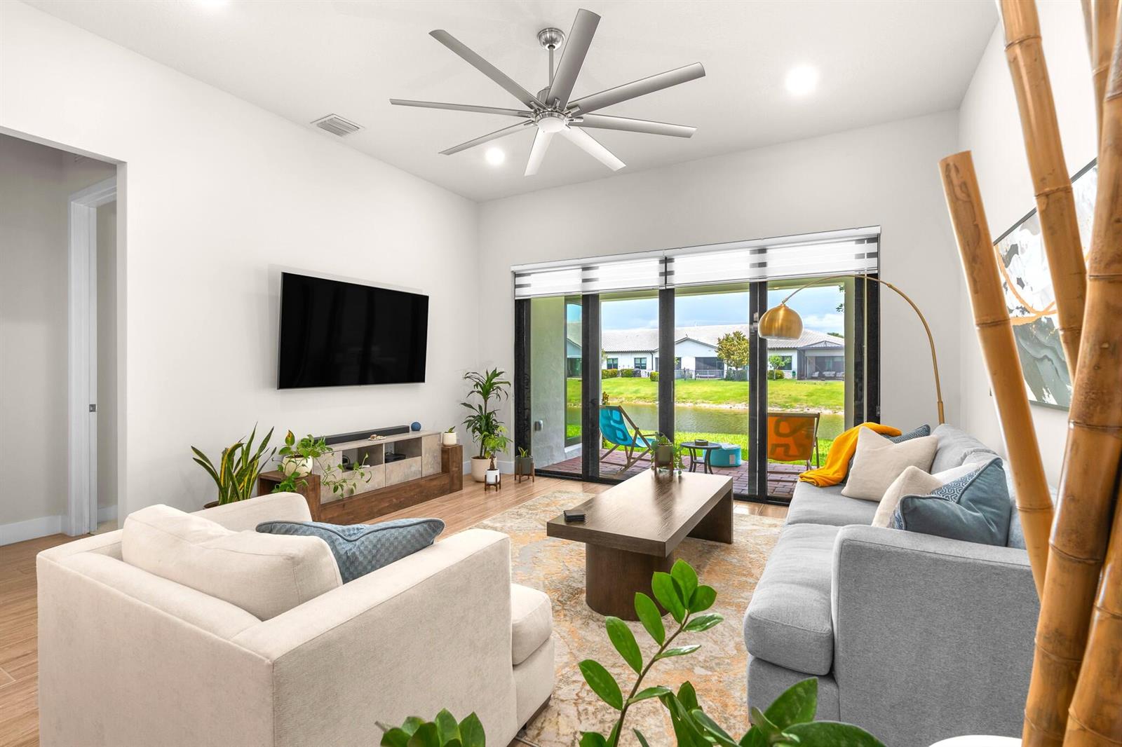 A living room features a grey sofa, white armchair, ceiling fan, and sliding glass patio doors — 7621 S Blue Spring Drive, Parkland FL 33067, PARKLAND, FL