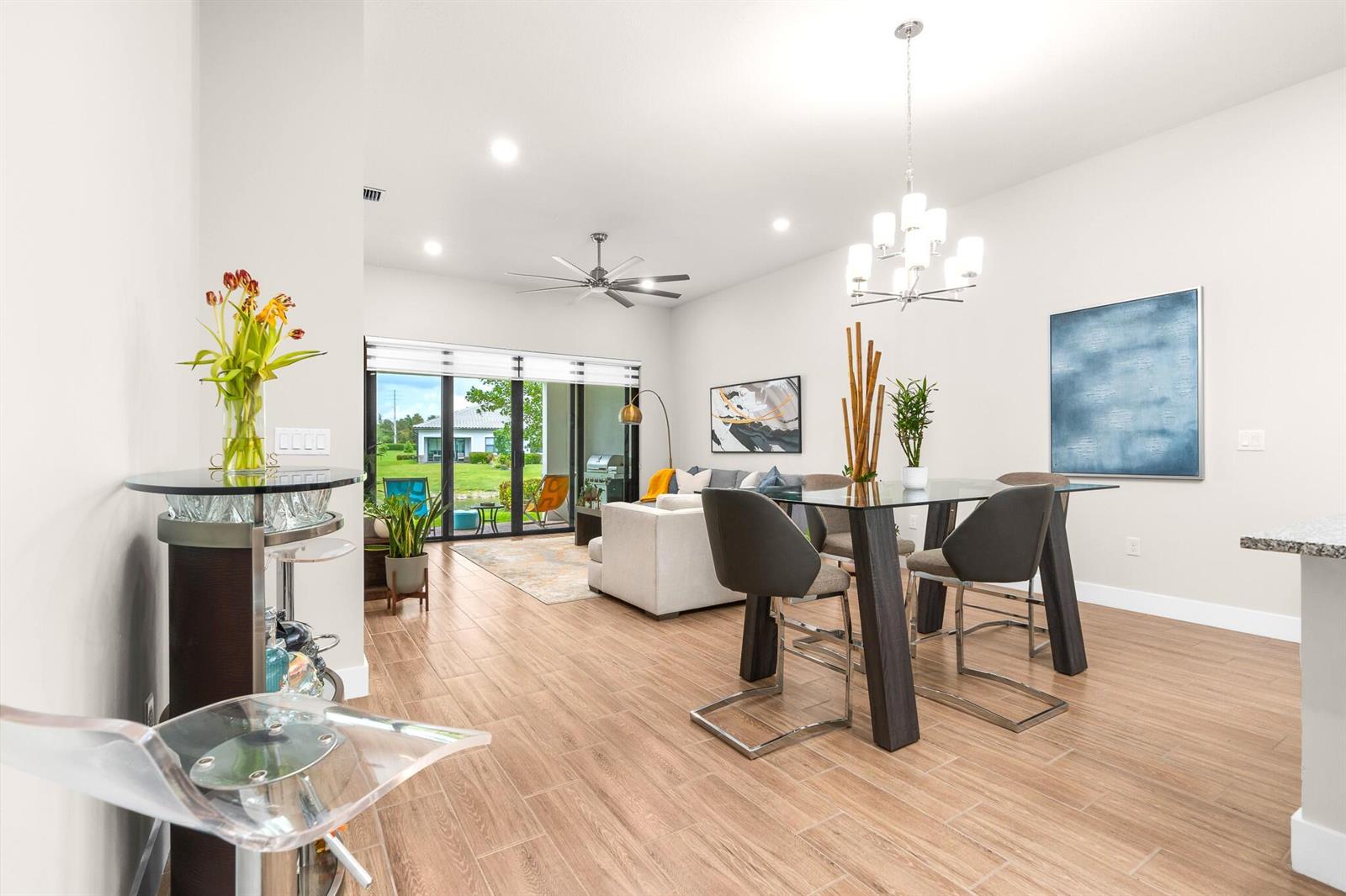 An open-concept living and dining area features tile flooring, a glass table, and sliding doors — 7621 S Blue Spring Drive, Parkland FL 33067, PARKLAND, FL