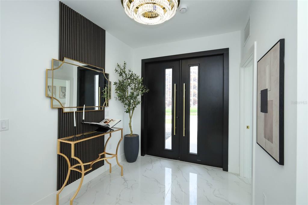 A modern entryway features a black double door, marble flooring, and a gold console table — 2360 OCEAN SHORE BOULEVARD UNIT 9, ORMOND BEACH, FL