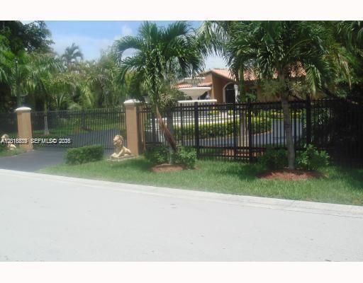 A black metal fence surrounds a driveway with a fountain in front of a house — 12425 SW 43rd St, Miami FL 33175, MIAMI, FL