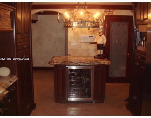 A kitchen island features a built-in wine refrigerator, granite countertop, and a decorative chef figurine — 12425 SW 43rd St, Miami FL 33175, MIAMI, FL