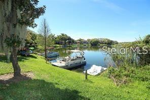A pontoon boat is docked on a calm lake surrounded by grassy banks and trees — 200 MAITLAND AVENUE UNIT 1, ALTAMONTE SPRINGS, FL