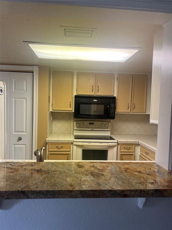 A kitchen features light wood cabinets, a black microwave, white appliances, and a granite countertop — 200 MAITLAND AVENUE UNIT 1, ALTAMONTE SPRINGS, FL